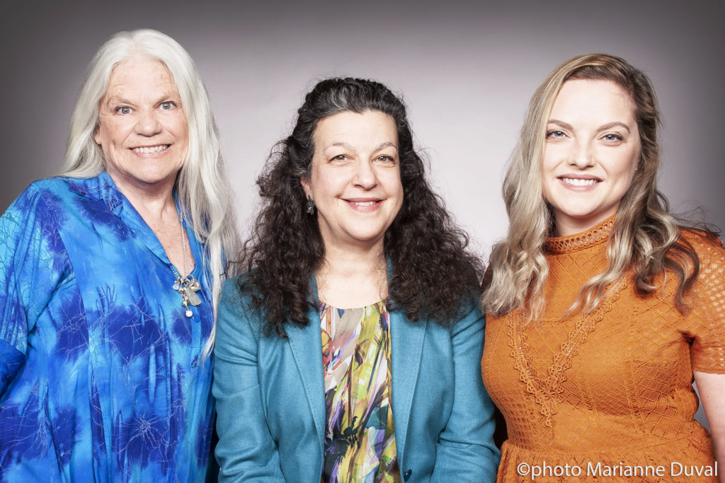 Three White women smile at the camera. / Trois femmes Blanches sourient à la caméra.