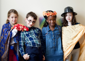 Four children in costumes smile. / Quatre enfants costumés sourient.