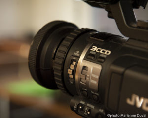 Close-up of a video camera, its lens and its buttons. / Gros plan d’une caméra, son objectif et ses touches.