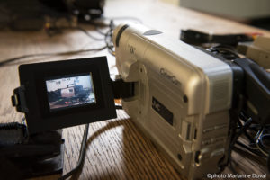 A close-up of a camcorder’s display monitor through which another older camcorder can be seen. / Un gros plan de l’écran d’un caméscope sur lequel se trouve un autre caméscope plus vieux.