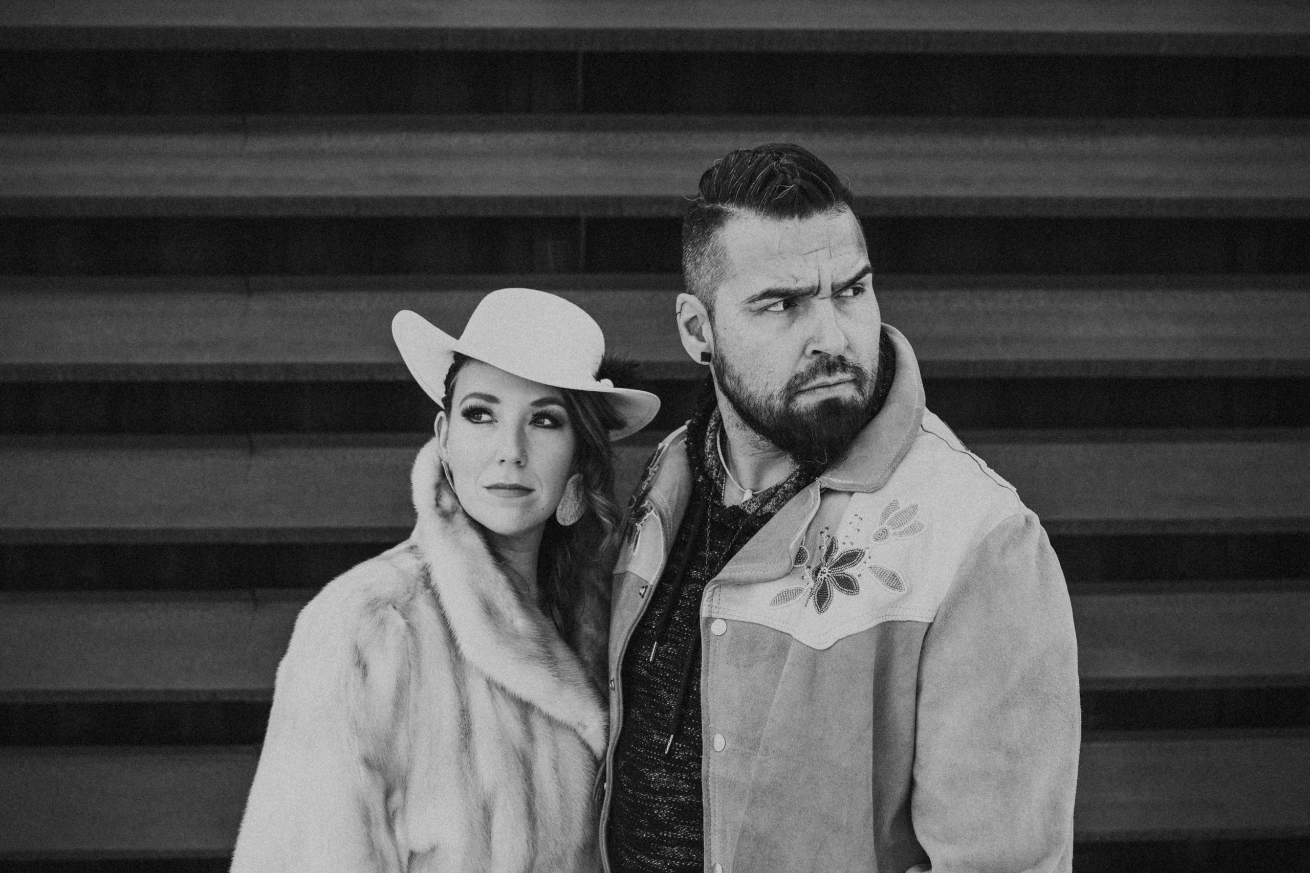 An Indigenous woman and man in black and white look into the distance. / Une femme et un homme autochtones, en noir et blanc, regardent au loin.