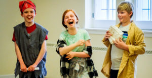 Three children in costumes laugh. / Trois enfants en costumes rigolent.