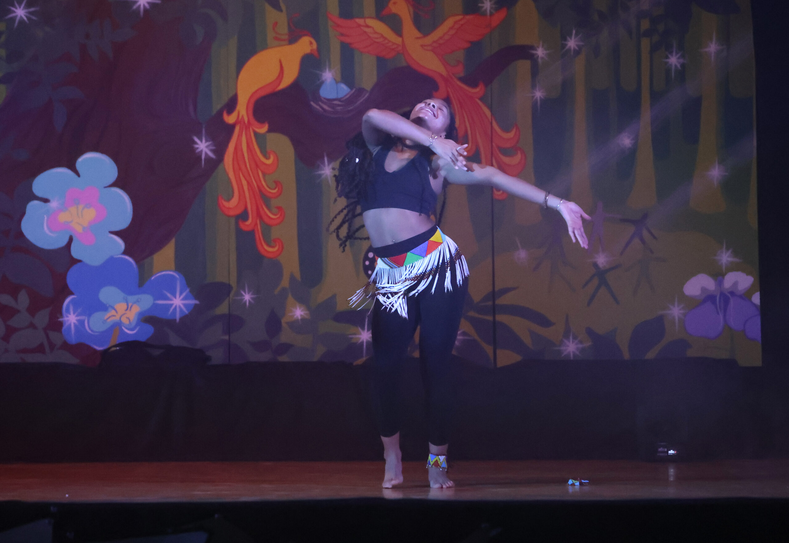 Julianne smiling and dancing, wearing colourful patterned outfit.